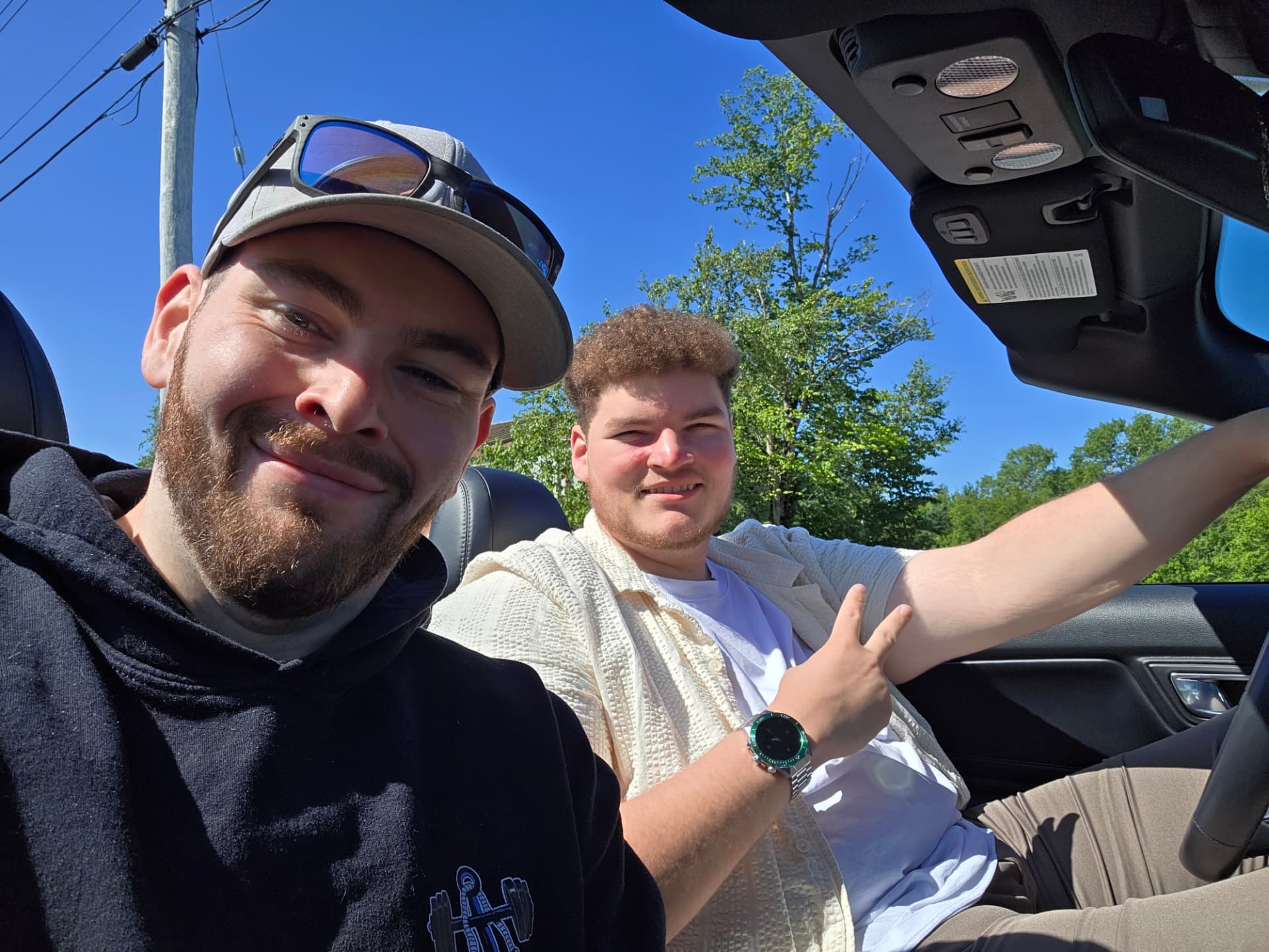 Two crew members taking a selfie in a convertible on a sunny day