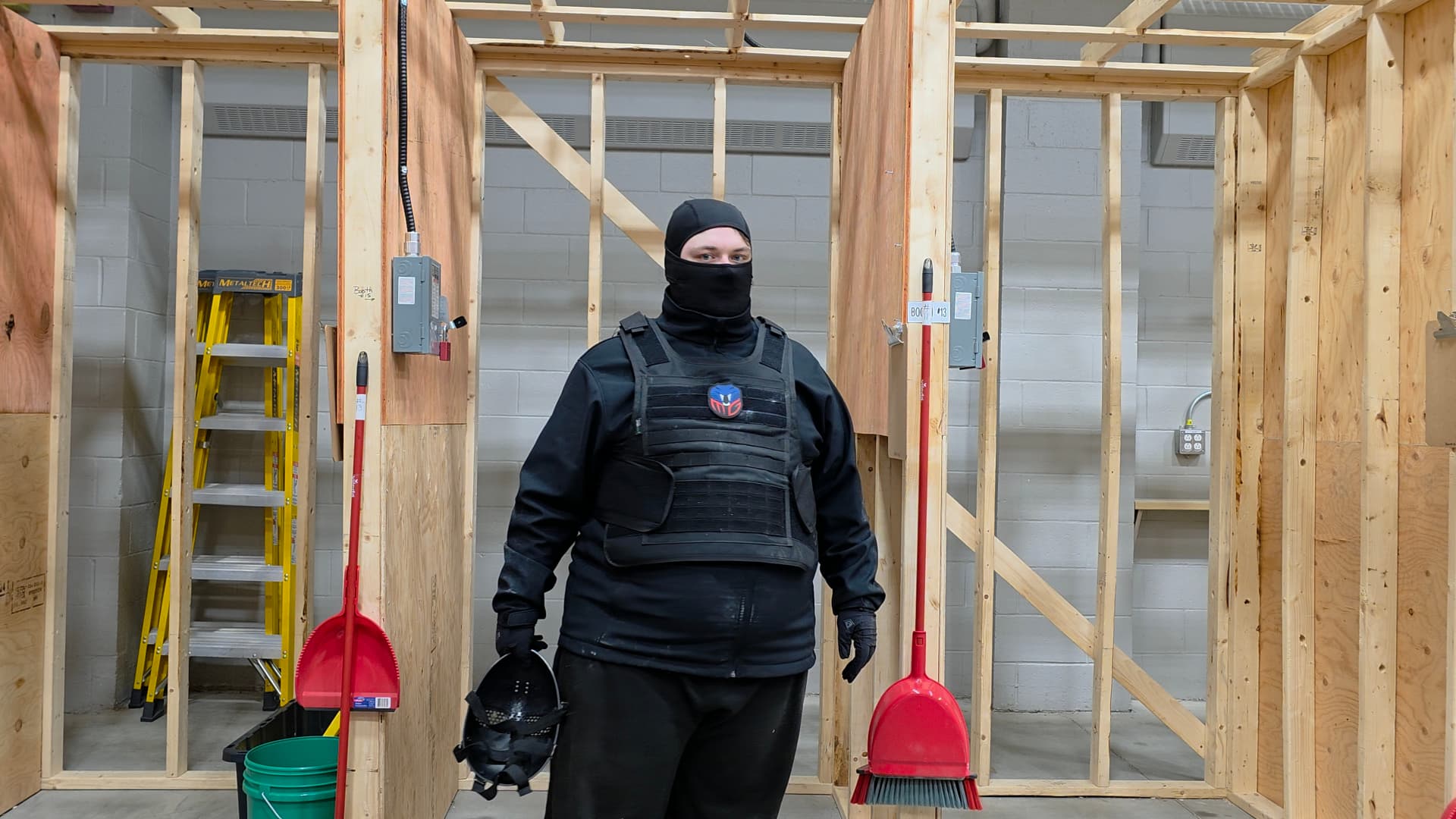 Masked actor in tactical costume standing inside a practical set