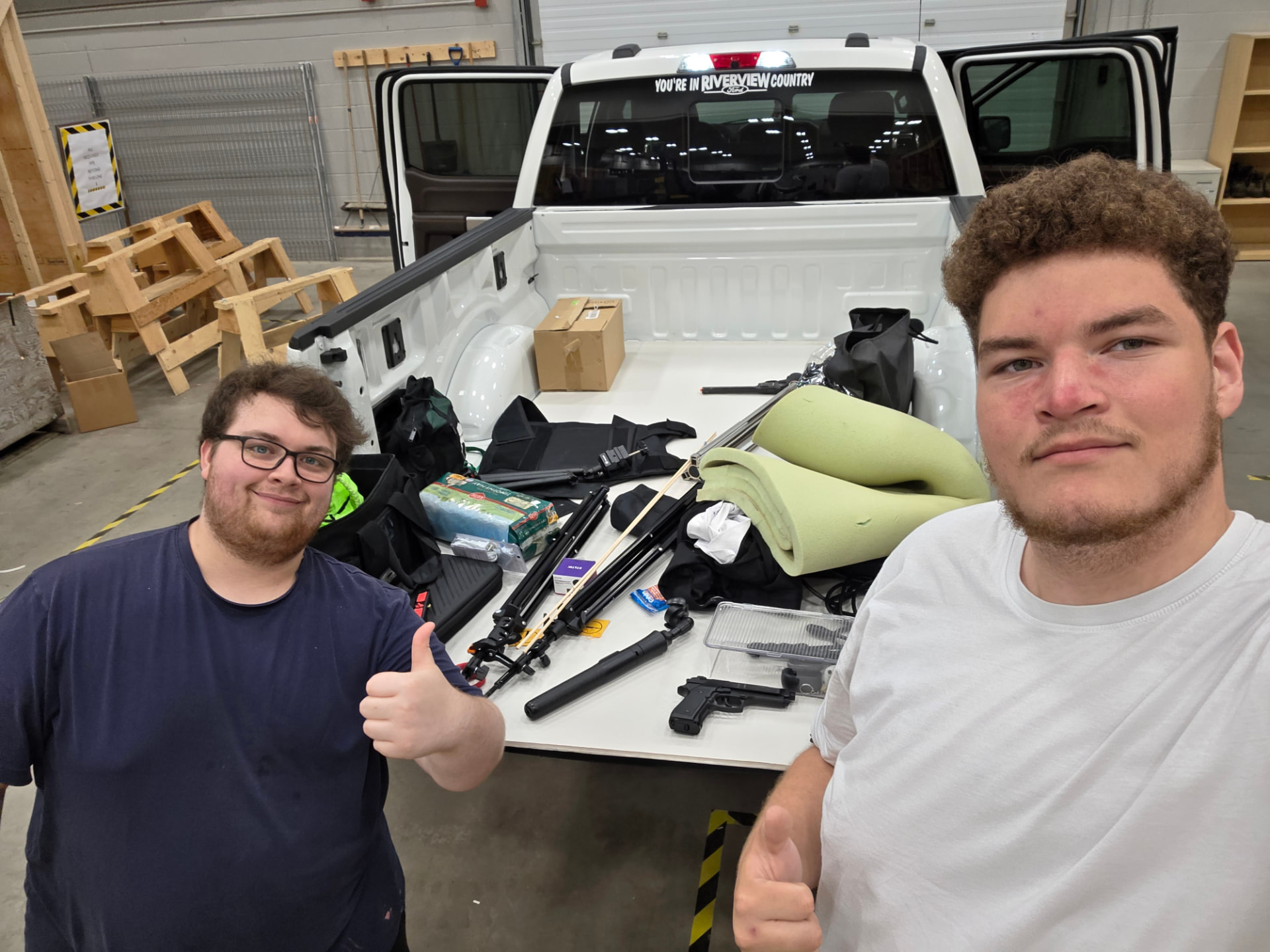 Two crew members with filming equipment arranged in a pickup truck bed