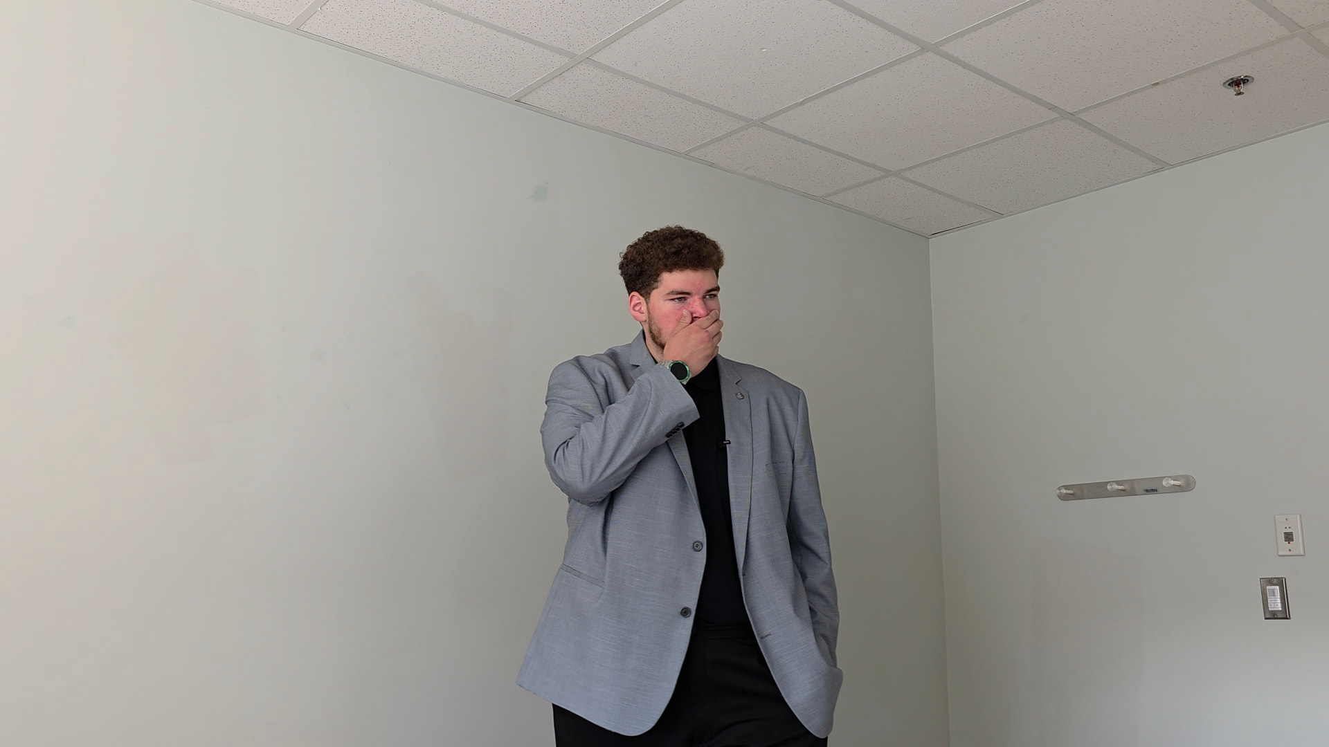 Actor in a grey suit rehearsing in an empty room