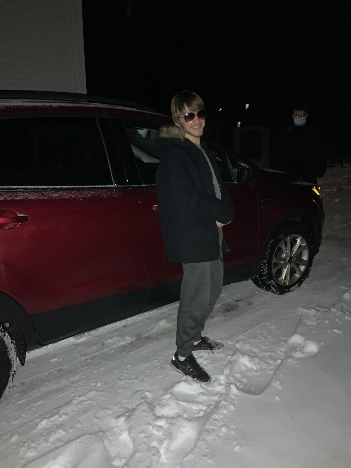 Performer standing beside a vehicle during a winter night shoot