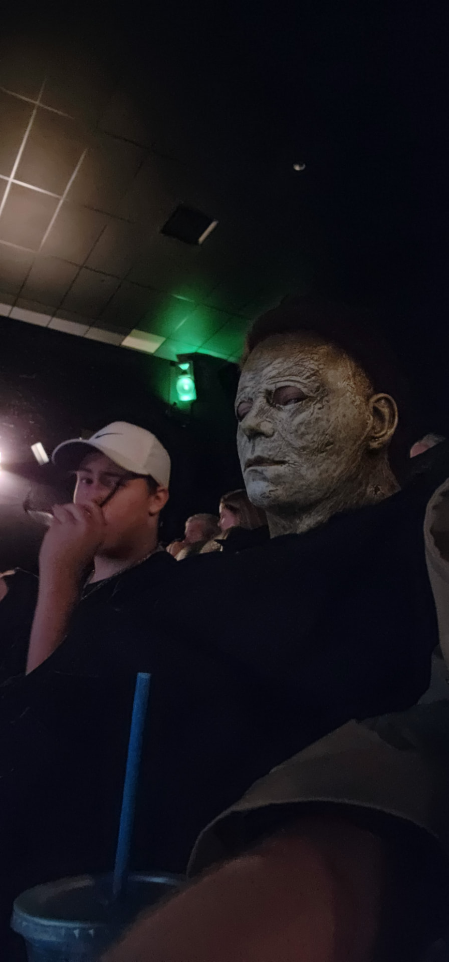 Michael Myers character seated beside a crew member in a cinema
