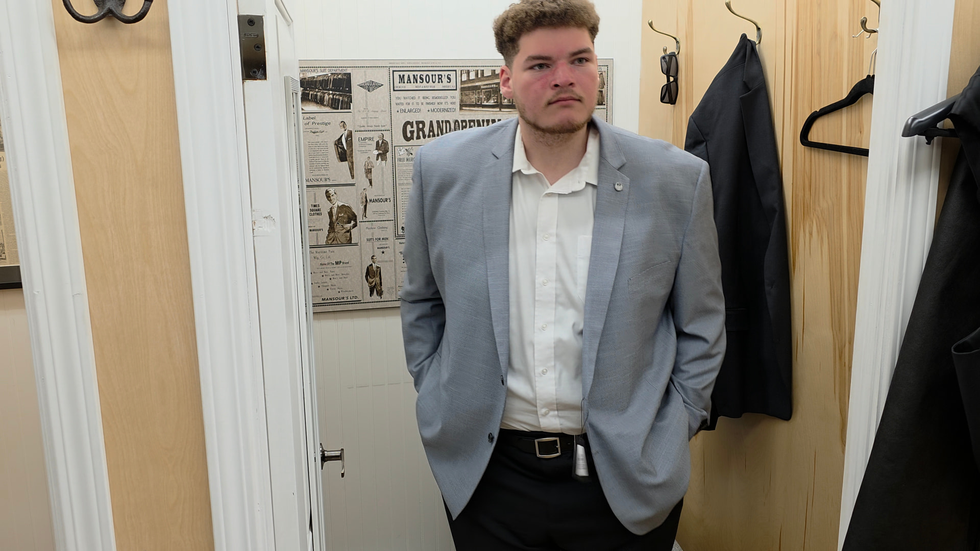 Actor in a light grey suit standing in a fitting room
