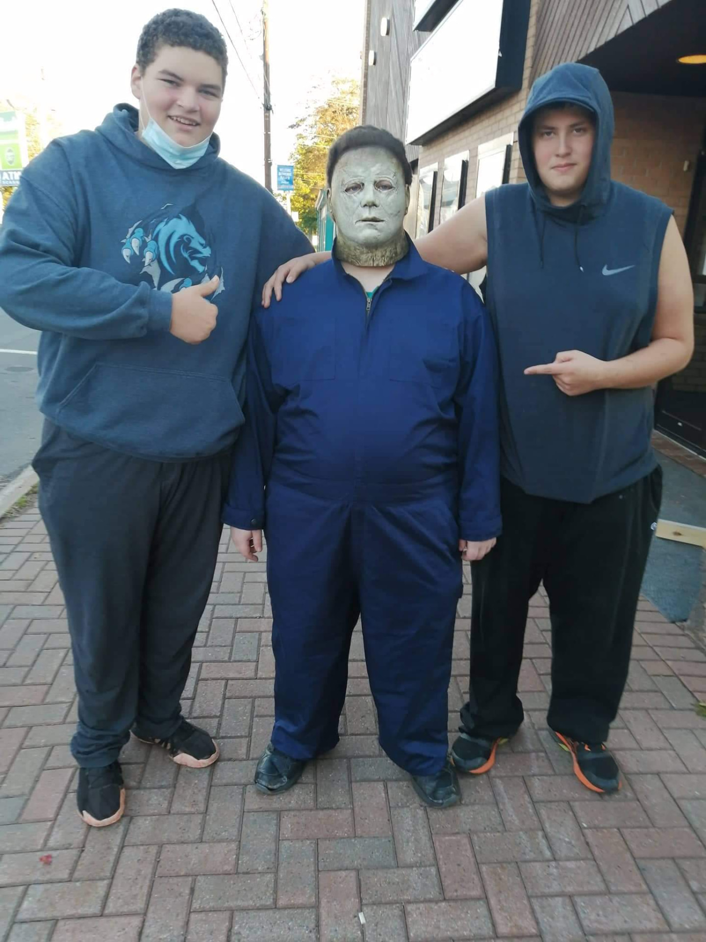 Two cast members posing with Michael Myers outside a cinema