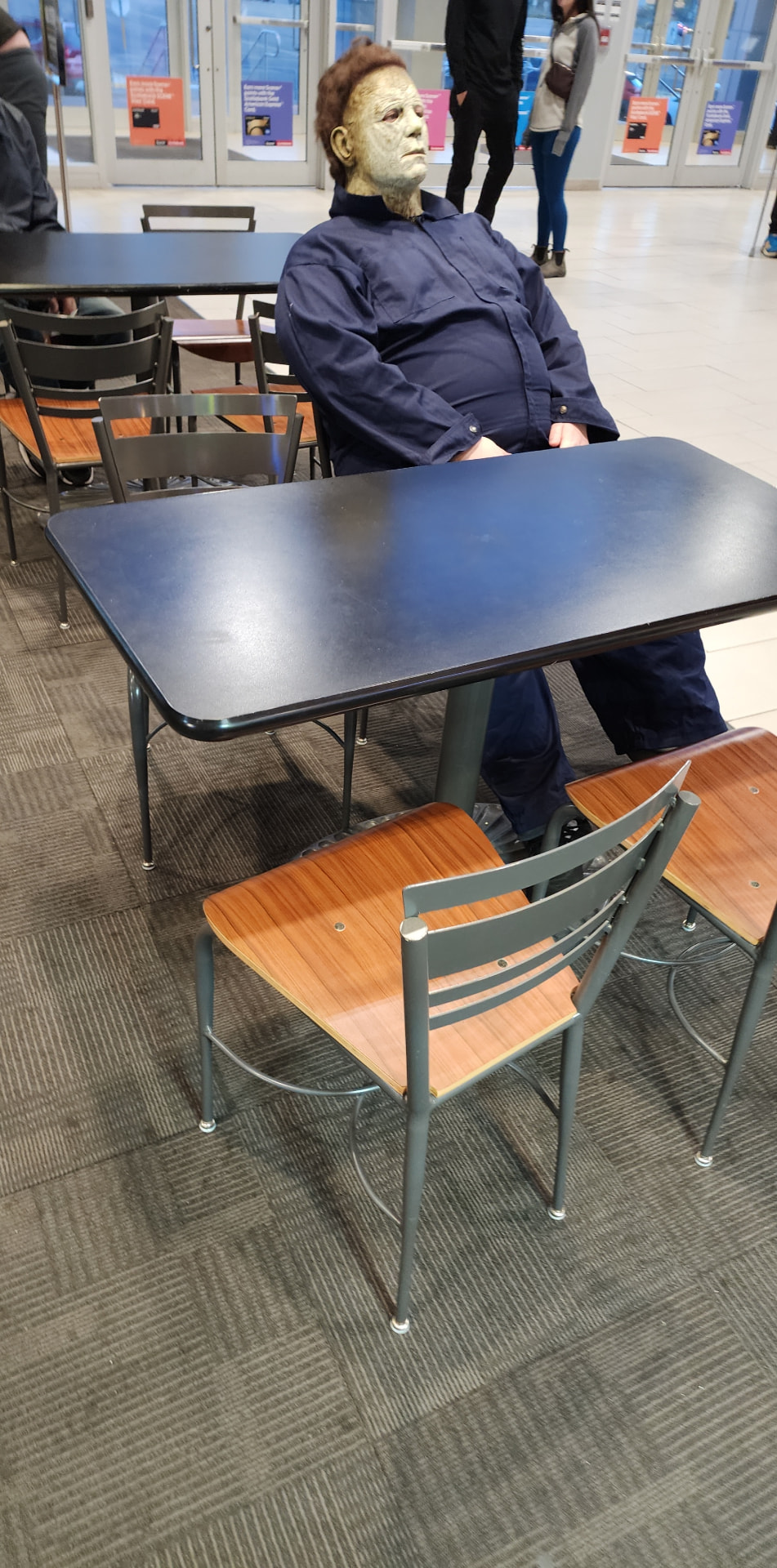 Michael Myers character seated at a cafeteria table between takes